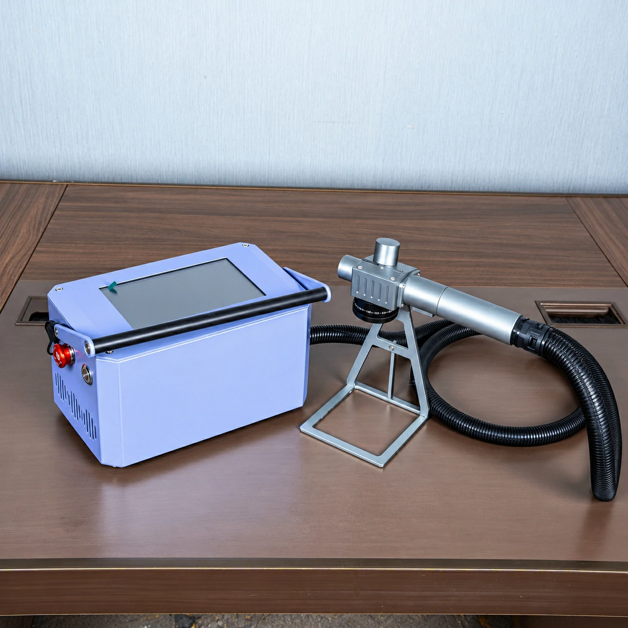 Portable fiber laser marking machine with handheld marking head and metal support stand on a worktable